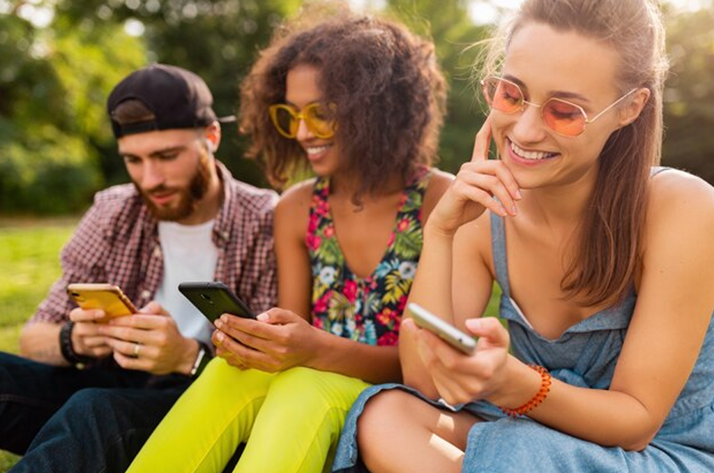 Diverse group of friends using smartphones outdoors